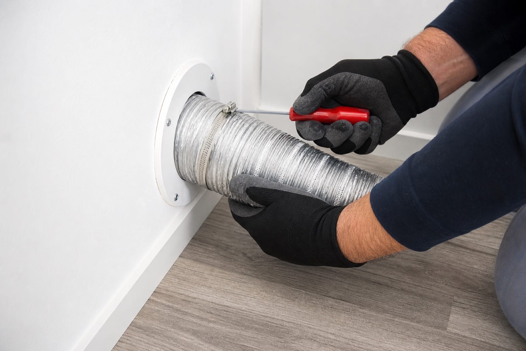 Photo-style illustration of a clean metal dryer vent duct connection being checked.